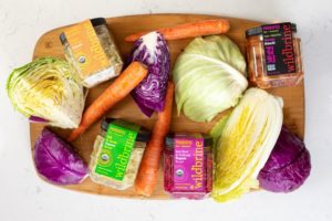 Varoius raw cabbage with wildbribe products in containers all on a wooden board